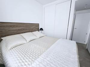 una camera da letto con un grande letto bianco con testiera in legno di Elegant Duplex Penthouse A116 a Las Lagunas Mijas Altre 33 foto