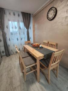 a dining room table with chairs and a clock on the wall at Apartment Premium in Topliţa