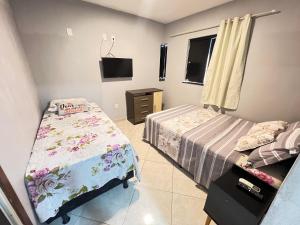 a bedroom with two beds and a tv in it at Kitnet a 1 Km da Orla in Aracaju