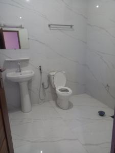 a white bathroom with a toilet and a sink at Femi in Dakar