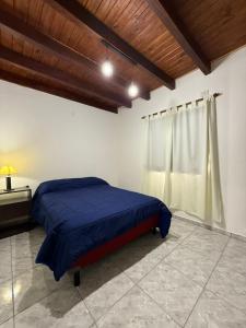 een slaapkamer met een blauw bed en een raam bij Sendero Patagonico in Las Grutas