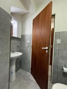 a bathroom with a sink and a wooden door at Sendero Patagonico in Las Grutas +27 photos