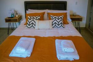 a large orange bed with two towels on it at Lodwine Lodge Apartments in Ciudad Lujan de Cuyo