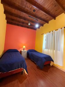 two beds in a room with yellow and orange walls at Sendero Patagonico in Las Grutas