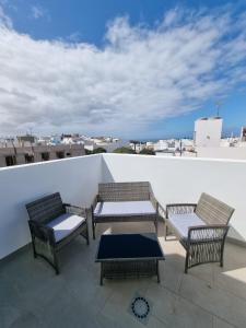 patio con 3 sedie e tavolo sul tetto di Hoy Cotillo Apartments a Cotillo