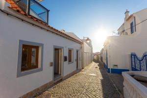 an alley with white buildings and the sun in the distance at tiny BEACH HOUSES - 2 min to Beach in Salema