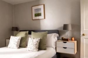 a bedroom with a bed with pillows and a night stand at Magnolia Cottage-Exclusive Cotswold Package in Moreton in Marsh