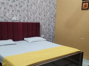 ein Bett mit weißen Laken und einem roten Kopfteil in einem Zimmer in der Unterkunft Panipat Town House - Top Rated Property of Panipat in Pānīpat