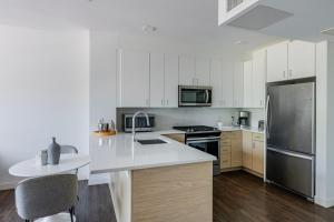 a kitchen with white cabinets and a stainless steel refrigerator at Blueground Newtonville rooftop nr Newton Centre BOS-1233 in Newton +33 photos