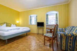een slaapkamer met een bed, een stoel en een televisie bij Hotel Bären Meersburg in Meersburg +7 foto's