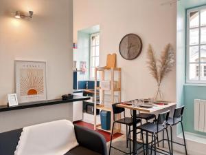 een kamer met een tafel en stoelen en een klok aan de muur bij Duplex - Place du Parlement de Bretagne - Hyper Centre de Rennes in Rennes