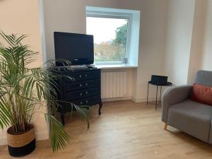 a living room with a tv on a dresser and a couch at Les Trinitaires in Sarzeau