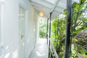 a porch with a white door and a hallway with plants at Rest Ahangama in Ahangama