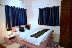 Schlafzimmer mit einem großen Bett und blauen Vorhängen in der Unterkunft Krishnayan Homestay in Ranchi