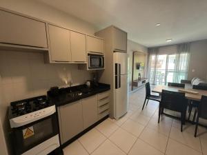 cód 39 · Apartamento com vista mar في جوفيرنادور سيلسو راموس: مطبخ مع دواليب بيضاء وطاولة مع غرفة طعام