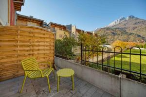 a patio with a chair and a stool and a fence at La Corte Delle Dolomiti in Agordo