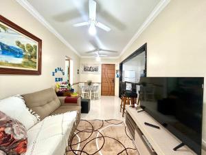 Una sala de estar con un sofá y un televisor de pantalla plana grande. en Ap Frente Mar, wi-fi, piscina, pet, check-in e check-out flexíveis, en Praia Grande