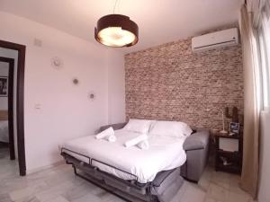 een slaapkamer met een bed en een bakstenen muur bij Amanecer Andaluz in Ronda +11 foto's