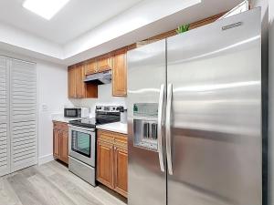 una nevera de acero inoxidable en una cocina con armarios de madera en 3BR Lake Front Getaway, en North Lauderdale