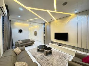 a living room with a couch and a tv at Dazzling Lekki 3BR Home - Private Balcony - 247 Power, Wifi & Security in Lekki