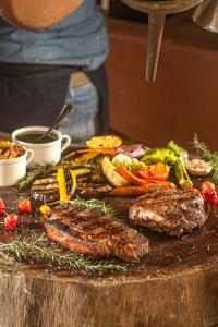 a table with meat and vegetables on a table at Pousada Fazenda Aroeira Secretário in Itaipava