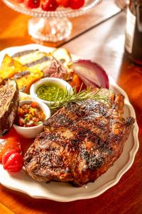 a plate of meat and other foods on a table at Pousada Fazenda Aroeira Secretário in Itaipava