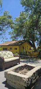 una casa amarilla con dos sofás en un patio en Coração do Rosa - com Piscina Jacuzzi charme e conforto Pertinho do centrinho do Rosa, en Praia do Rosa