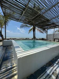 a swimming pool with an umbrella and palm trees at Casa Origen Boutique en San Bernardo del Viento in San Bernardo del Viento
