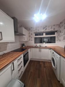 a kitchen with white cabinets and a washer and dryer at Comfortable two bed apartment in Chester-le-Street