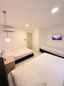 a bedroom with two beds and a tv on the wall at The Host apartamentos At Los Angeles in Santa Marta