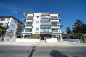 New 2 bedroom flat in Aglantzia في Aglantzia: مبنى شقق بيضاء على جانب شارع