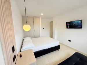 a bedroom with a bed with a tv on the wall at The Host apartamentos At Los Angeles in Santa Marta +3 photos