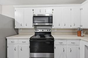 een keuken met witte kasten, een zwarte kachel en een magnetron bij Modern Highland Park 2BR 2BA Stay in Clarksville