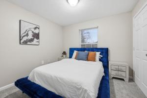 een slaapkamer met een blauw bed en een raam bij Modern Highland Park 2BR 2BA Stay in Clarksville