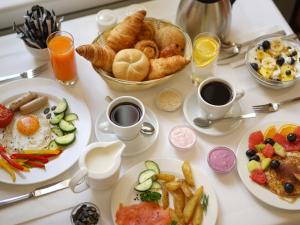 a table with plates of breakfast foods and cups of coffee at Thermal Hotels & Walliser Alpentherme Leukerbad in Leukerbad
