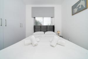 New 2 bedroom flat in Aglantzia في Aglantzia: غرفة نوم بيضاء مع سرير أبيض كبير مع وسائد بيضاء