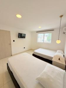 a bedroom with two beds and a tv on the wall at The Host apartamentos At Los Angeles in Santa Marta
