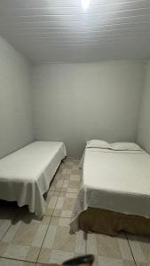deux lits dans une petite pièce aux murs blancs dans l'établissement Beach Loft, à Vila Velha