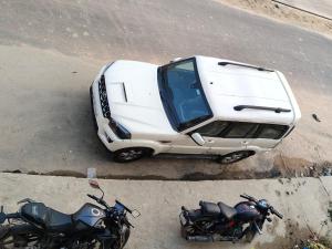 Un coche blanco aparcado junto a una moto y una furgoneta. en ABS Palace Ayodhya, en Faizābād