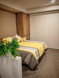 a bedroom with a bed with a yellow blanket at Loft Centro Zapopan in Guadalajara