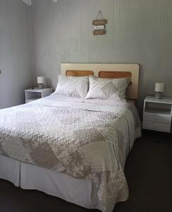 Un dormitorio con una gran cama blanca con dos mesitas de noche. en Refugio del bosque, en Chaitén