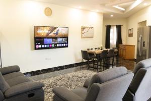 een wachtkamer met een tafel en stoelen en een tv bij BethelAirBnB in Winneba