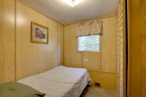 a small bedroom with a bed and a window at Little Manistee Riverfront Cabin with Fire Pit! in Irons
