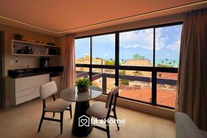 une pièce avec une table et des chaises et une grande fenêtre dans l'établissement Hit Cabo Branco - LikeHome Hospedagens, à Tambaú