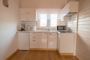 a kitchen with white cabinets and a sink and a window at Domki u Wojtka in Grywałd