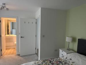 a white bedroom with a bed and a mirror at Cozy Flat for 2 River of Thames with FREE Parking in Staines