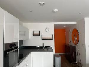 a kitchen with a sink and a clock on the wall at Cozy Flat for 2 River of Thames with FREE Parking in Staines