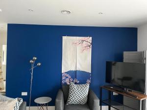 a living room with a blue wall and a tv at Cozy Flat for 2 River of Thames with FREE Parking in Staines +1 photo