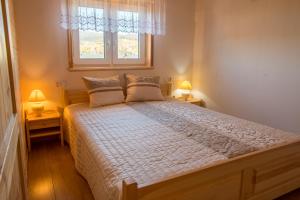 a bedroom with a large bed with two lamps at Domki u Wojtka in Grywałd