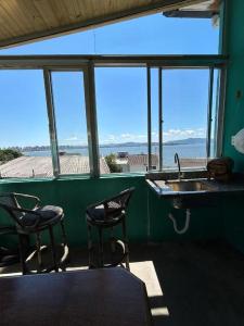 una stanza con due sedie, un lavandino e delle finestre di Casa Maria Mar a São José